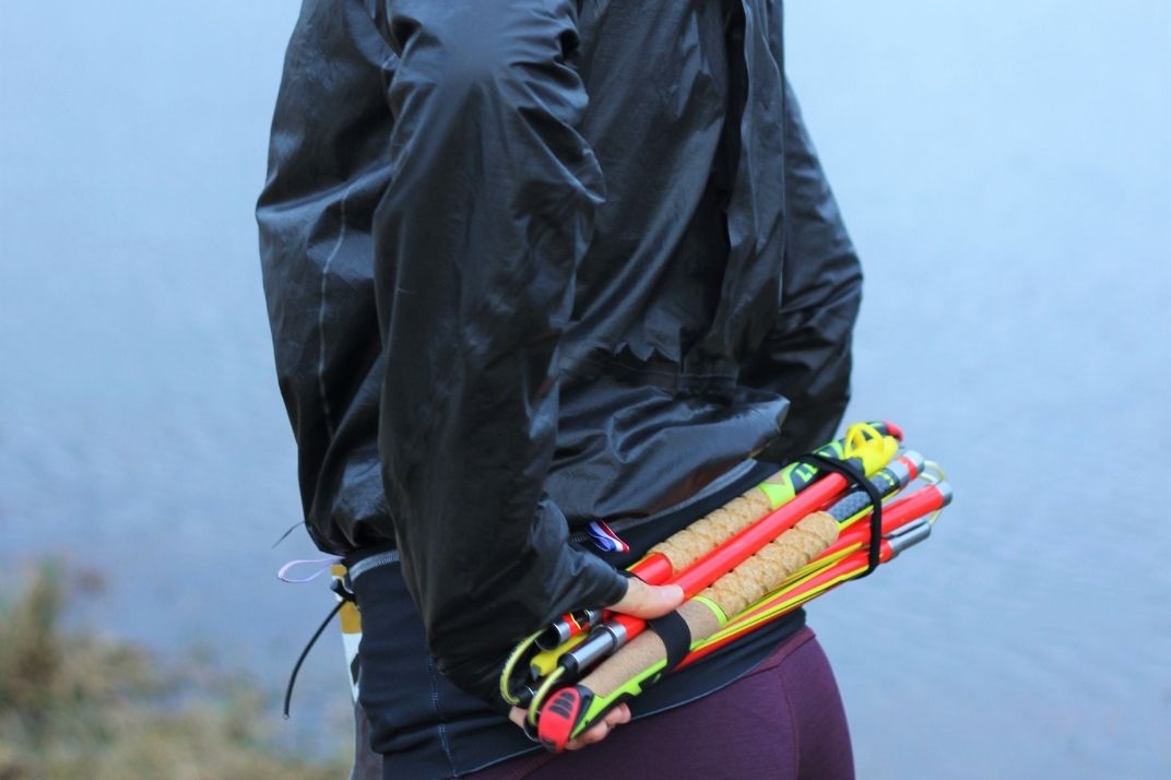 Une femme qui prend des bâtons pliables de trail depuis la ceinture de trail