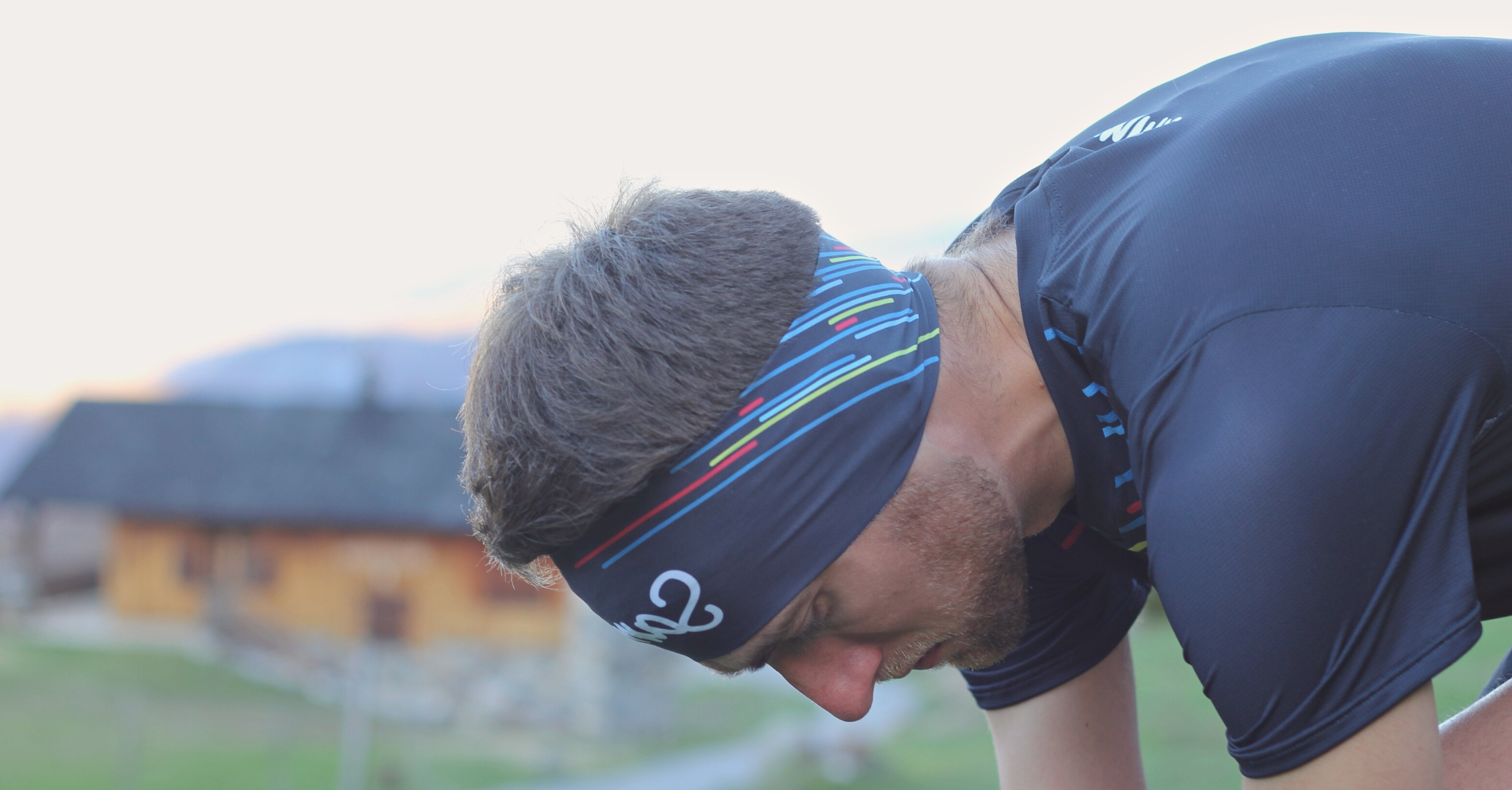 Un homme qui fait ses lacets avec le bandeau running sur les oreilles