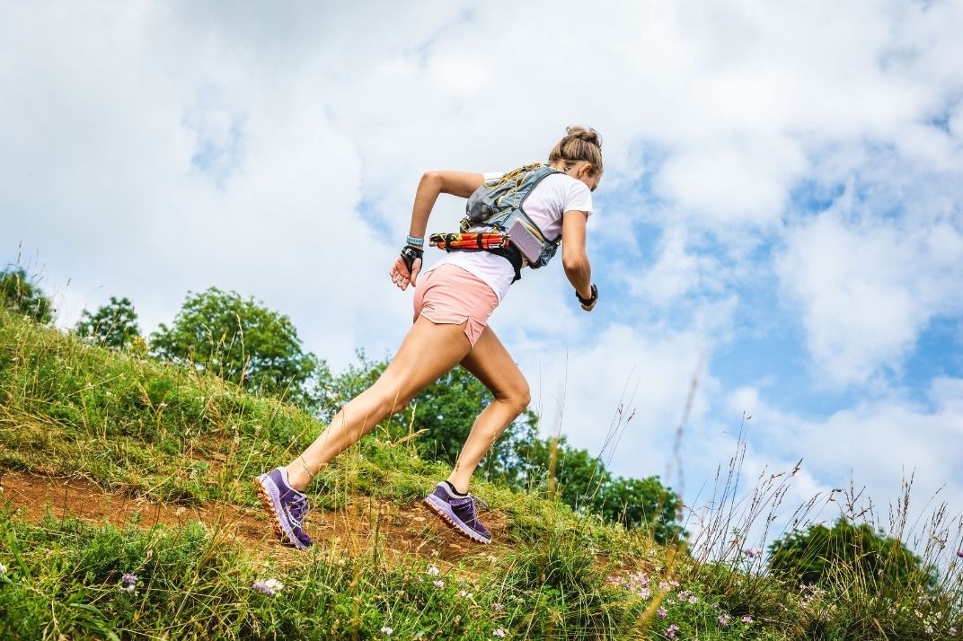 femme qui court avec le port bâtons trail