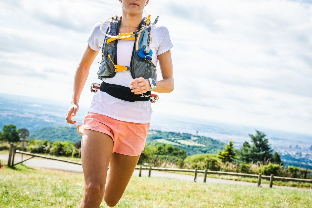 femme qui court avec le porte bâtons trail en pleine nature